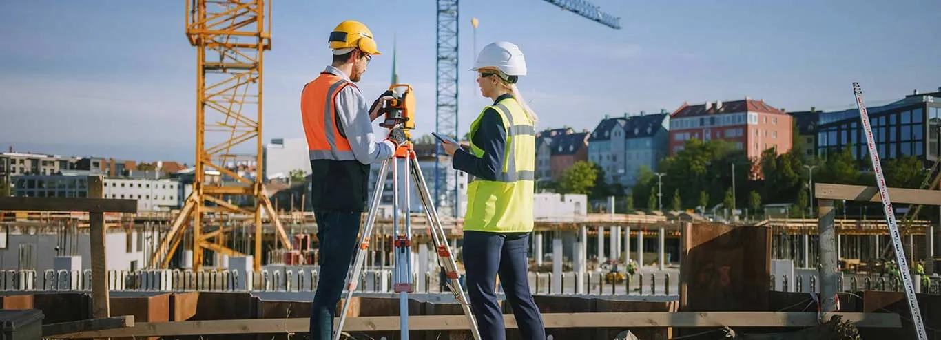 2 contractors using surveying equiptment at a construction site