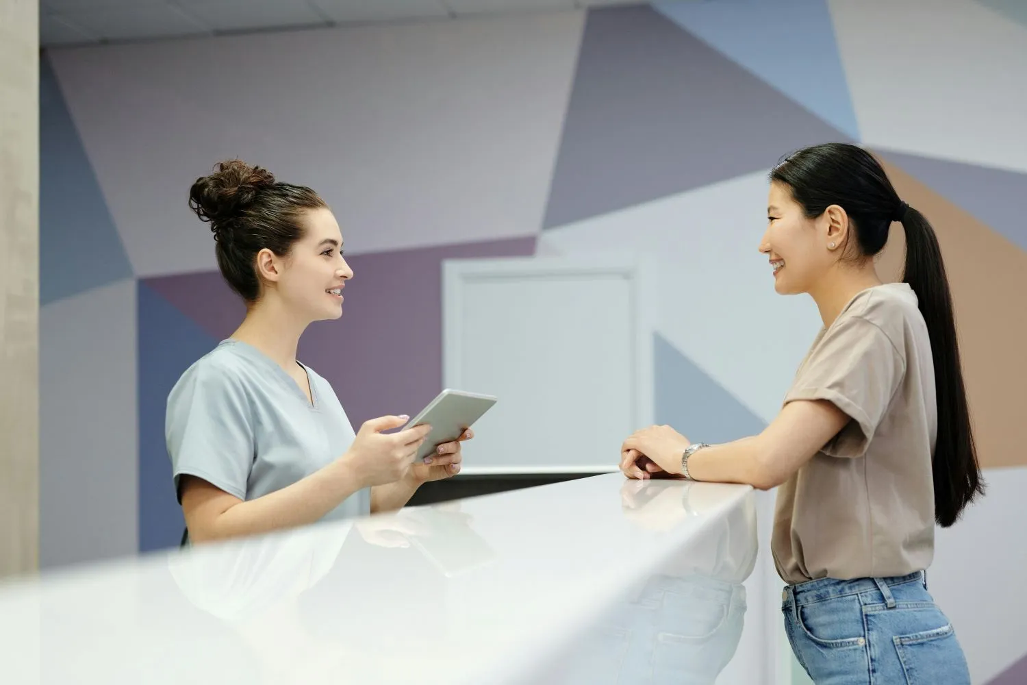 Visitor signing in at a medical clinic reception desk using a tablet