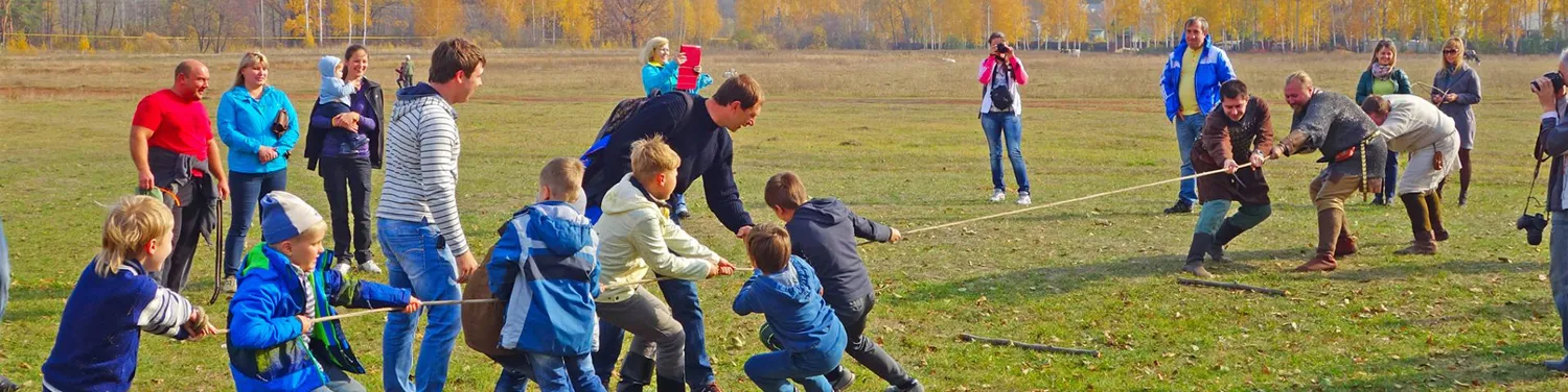 a group of children playing tug-of-war with volunteers