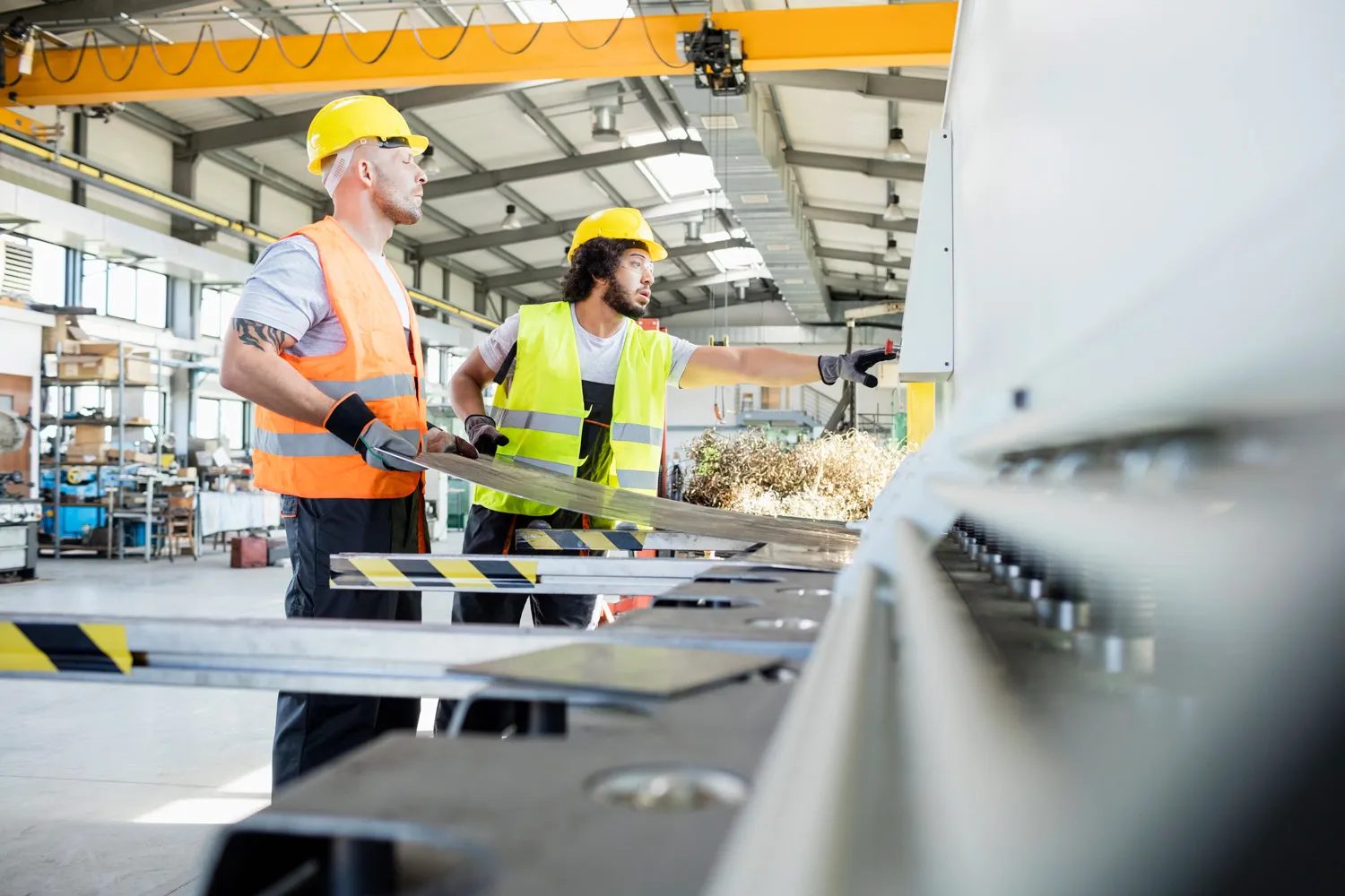 two manufacturing workers in hi-vis operating machinery