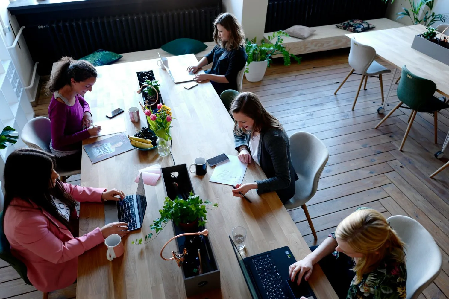Employees working around a large wooden table in a modern sunlight office
