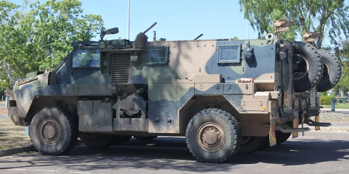 Camouflaged Bushmaster armoured vehicle parked in a carpark next to an eucalyptus tree. Image represents how Thales Group managed contractor onboarding.