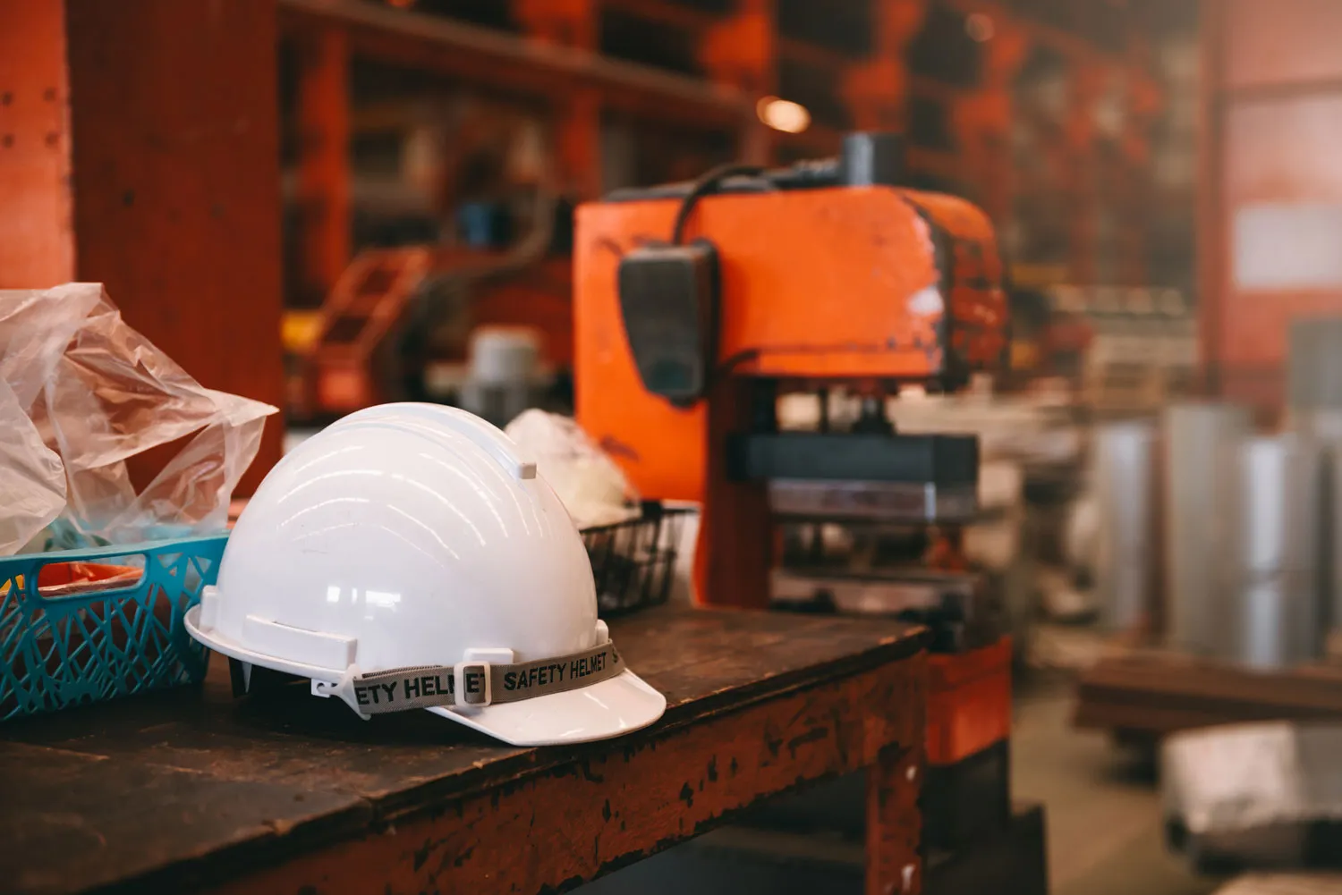 Photograph of a hardhat on a workbench in a woodworking shop, with tools in the background.